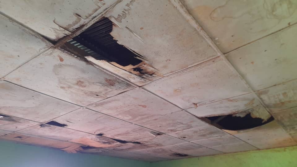 Severely damaged classroom ceiling panels with large openings at GBPS Bafoussam Group 2B before rehabilitation